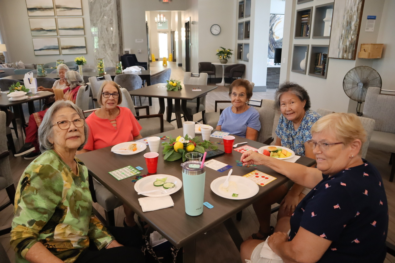 A group of community guests smiling around a bingo table